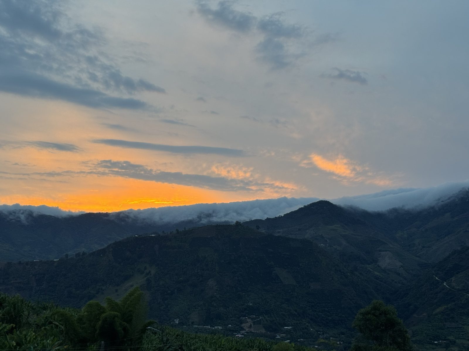 Atardecer sobre una cordillera: un banco de nubes desciende sobre las montañas y el cielo arde en naranja